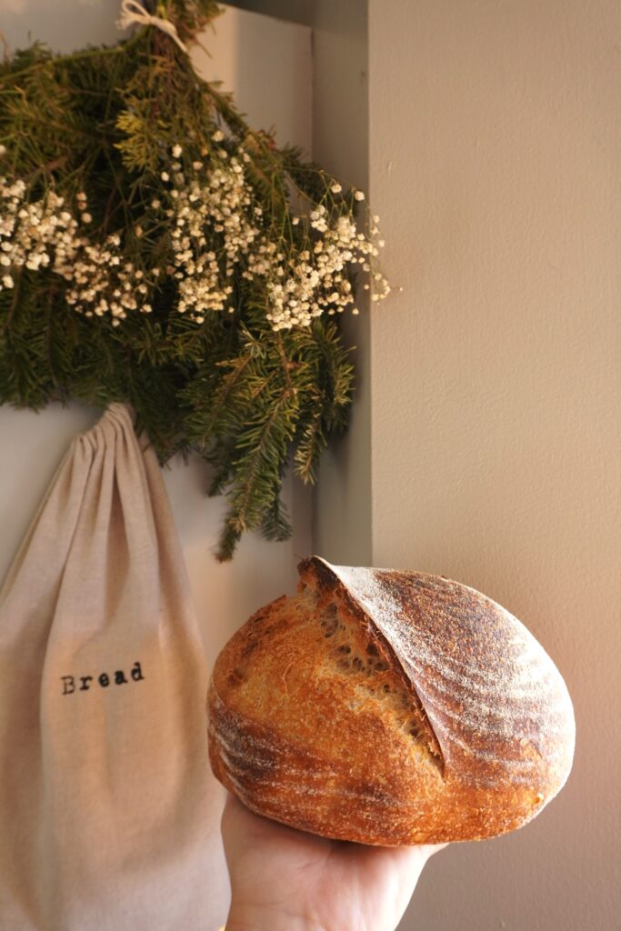 a round rustic sourdough loaf being held in hand