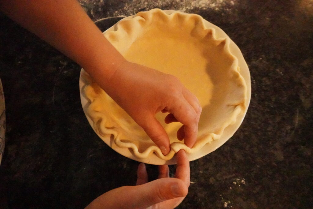 pie dough edges being crimped for summer quiche 