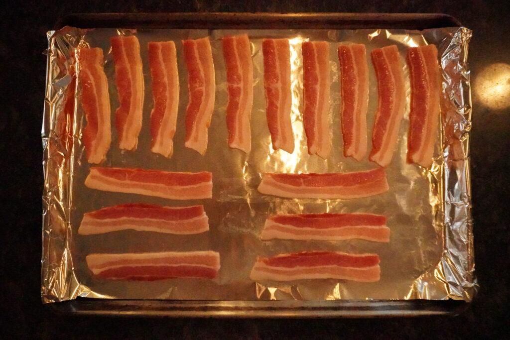 raw bacon on a baking sheet