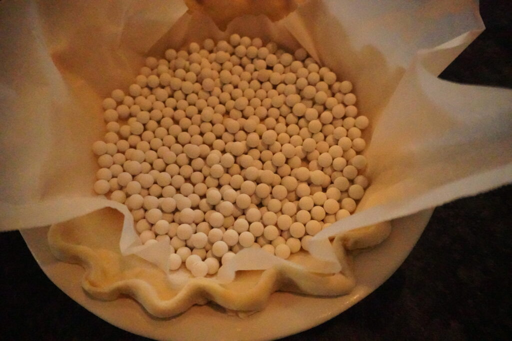 pie weights sitting in a parchment paper lined pie crust